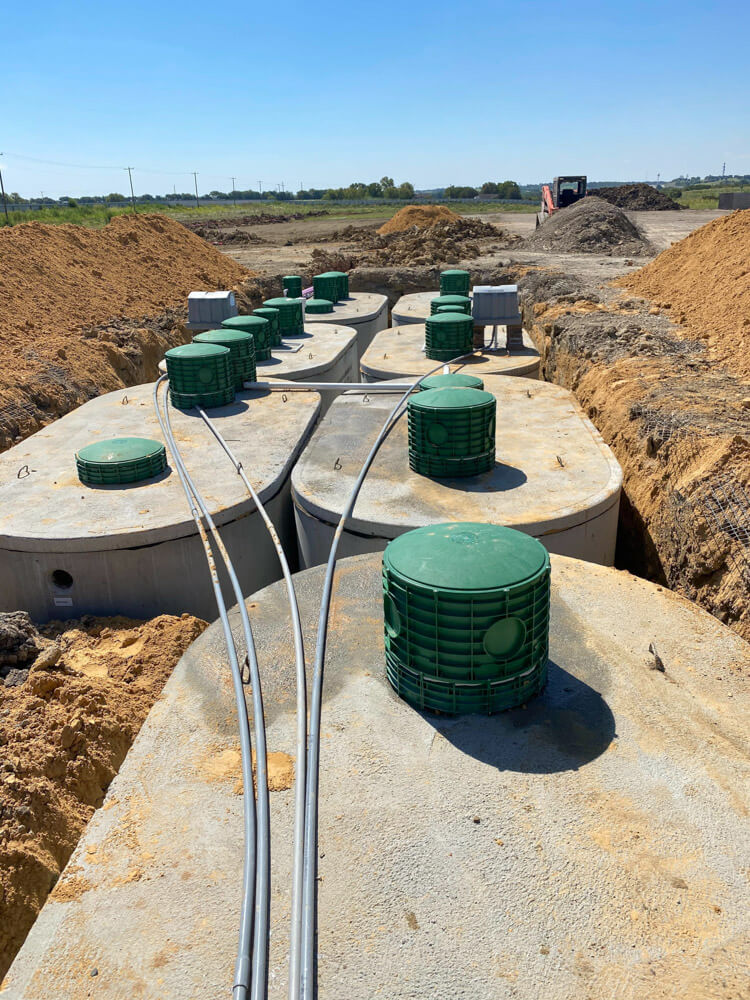 A row of concrete septic tanks installed in the ground