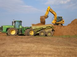 Trackhoe loading a John Deere with a pull type pan.