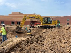 komatsu excavator digging beside a school