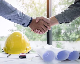 Shaking hands of collaboration, Construction engineering or architect discuss a blueprint while checking information on drawing and sketching, meeting for architectural project of partner.